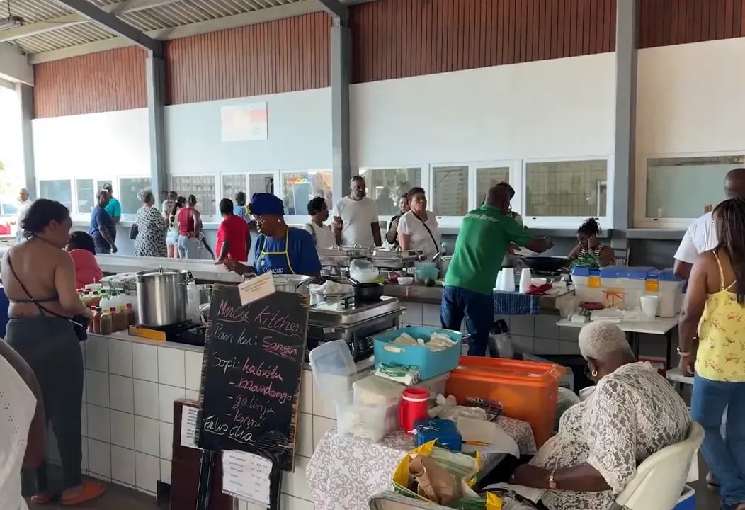 Busy covered market hall with food stalls, tables, and people dining